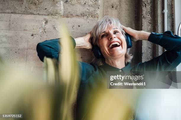 cheerful businesswoman listening music through headphones in office - woman on gray background stock pictures, royalty-free photos & images