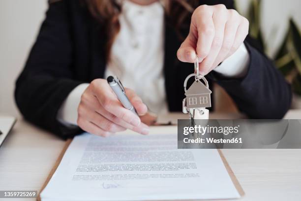 saleswoman holding house keys and pen at office - handing over keys stock pictures, royalty-free photos & images