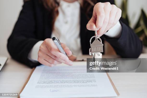 saleswoman holding house keys and pen at office - till uthyrning bildbanksfoton och bilder