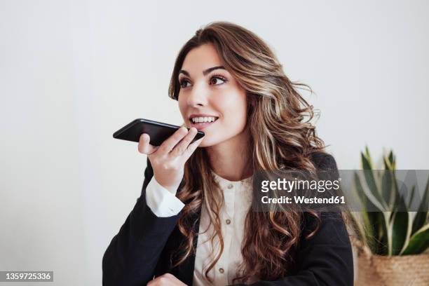 young businesswoman sending voice mail through smart phone at office - sending stock pictures, royalty-free photos & images
