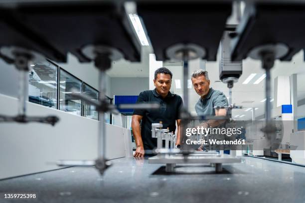 engineers discussing over machinery at factory - línea de producción fotografías e imágenes de stock