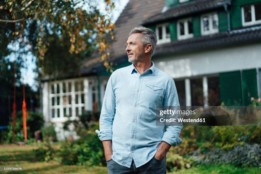 Man with hands in pockets standing at backyard