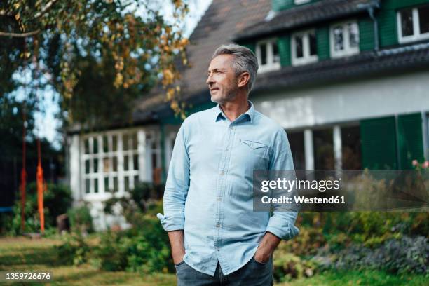 man with hands in pockets standing at backyard - 50 54 years outdoors stock pictures, royalty-free photos & images