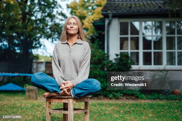 woman practicing yoga on stool at backyard - meditation outdoors fotografías e imágenes de stock