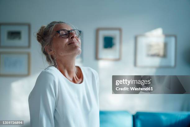 smiling woman with eyes closed at home - daydreaming stock-fotos und bilder