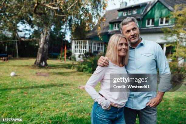 smiling man with arm around woman at backyard - couple standing stockfoto's en -beelden