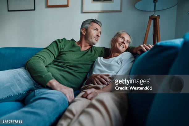 couple relaxing on sofa in living room - 55 couple ストックフォトと画像