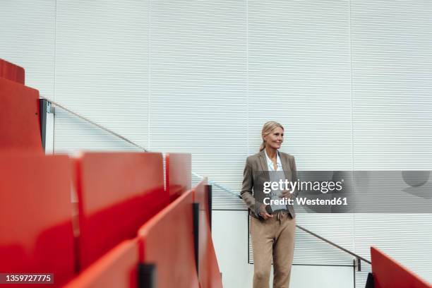 businesswoman with mobile phone standing at auditorium - docent stockfoto's en -beelden