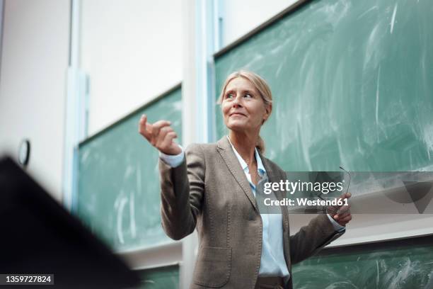 businesswoman giving presentation by chalkboard at convention center - lecturer fotografías e imágenes de stock