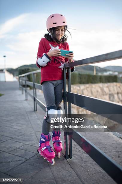 skater girl looks at her smartphone while doing her activity, during a break - 7 fotografías e imágenes de stock
