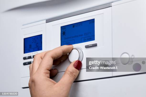 cropped hand of woman adjusting knob on heating boiler's control panel - caldera fotografías e imágenes de stock