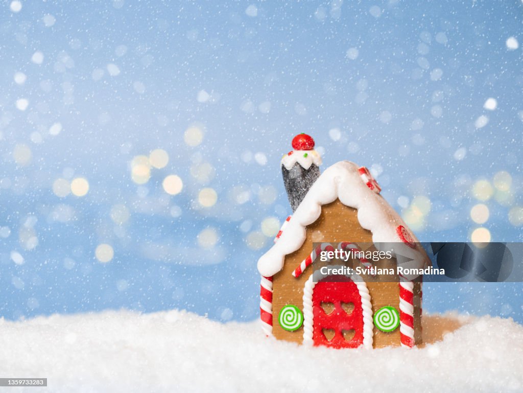 Christmas card with Gingerbread house , snow and Christmas lights illumination with bokeh