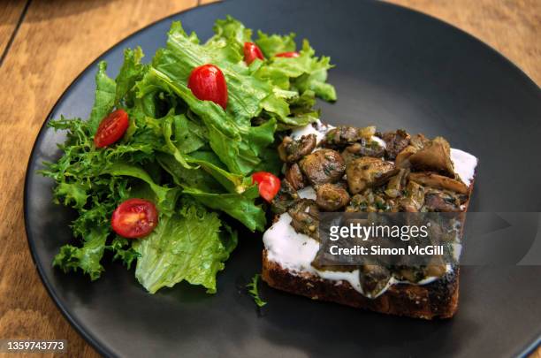 toasted bread with a cream spread, roasted mushrooms with pesto and fried onions, and a side salad of red grape tomatoes and lettuce - side salad stock pictures, royalty-free photos & images