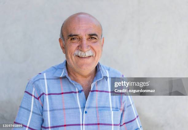 close up portrait of a mature man over white wall, daylight photo - smiling mature eyes stockfoto's en -beelden