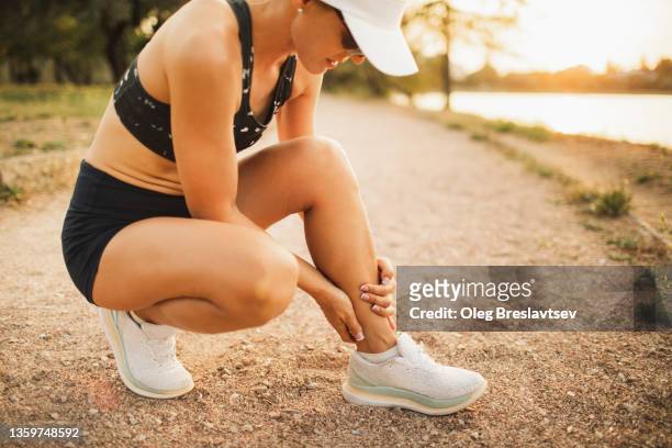 woman hands holding injured achilles or calf muscle. sprain ligament on running - female muscular calves fotografías e imágenes de stock