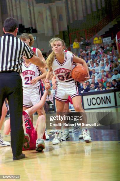 Point guard Pam Weber of the University of Connecticut helps an opponent off the floor as she waits for a call by the referee, Storrs CT 1995.