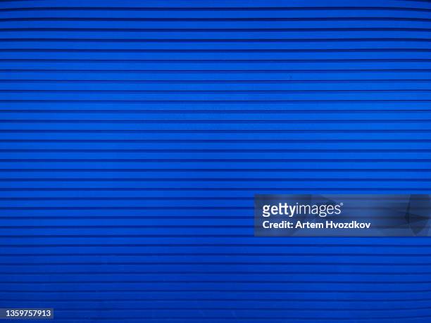 saturated deep  blue-colored , roller shutter door. full frame, front view - industrial door stock pictures, royalty-free photos & images