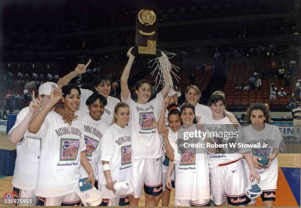 UConn star Rebecca Lobo, center and surrounded by teammates, raises the NCAA trophy in a victorious gesture after after winning the finals against...