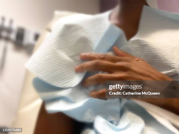 african-american woman wearing patient gown while waiting for doctor in examination room - hospital gown fotografías e imágenes de stock