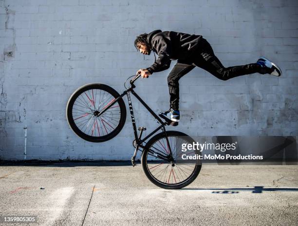 young male bmx rider performing wheelie in urban area - live georgia show stock-fotos und bilder
