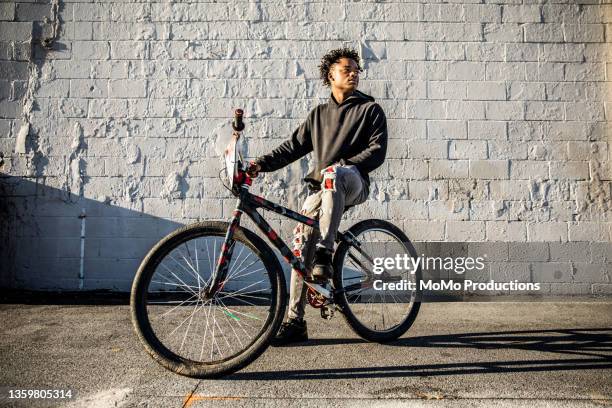 portrait of young male bmx rider in urban area - wheelie stockfoto's en -beelden