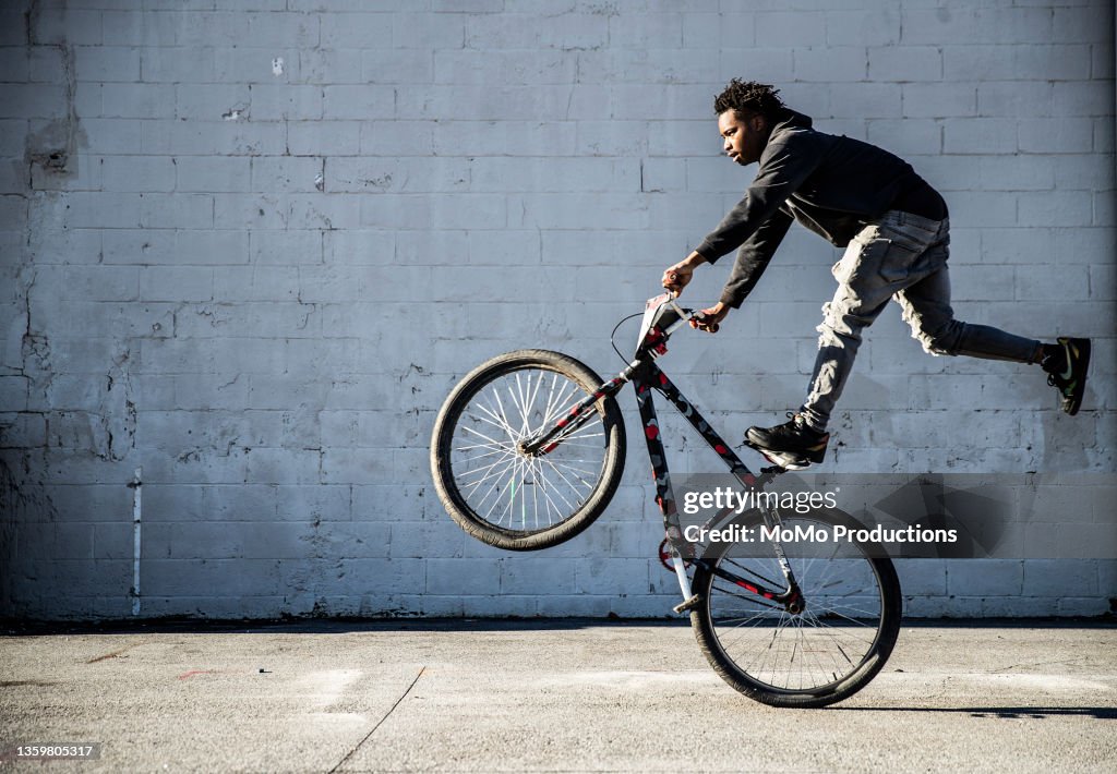 Young male BMX rider performing wheelie in urban area