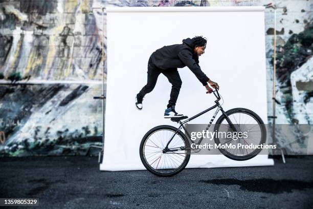 young male bmx rider performing wheelie in front of white backdrop - live georgia show stock pictures, royalty-free photos & images