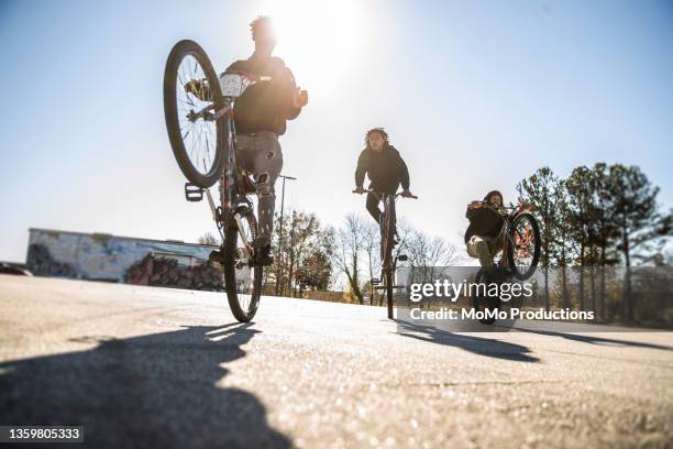 young male bmx riders performing wheelies in urban area - スタントバイク ストックフォトと画像