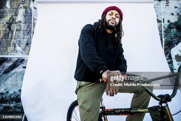 portrait of young male bmx rider in front of white backdrop - low angle view street stock-fotos und bilder