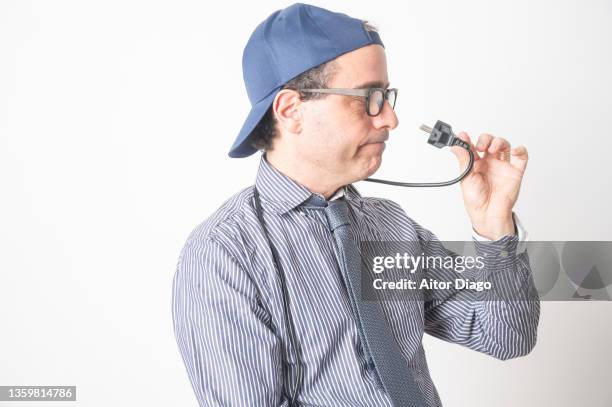 entrepreneur looks at  an electric cable which holds in his hand - hand gag stock-fotos und bilder