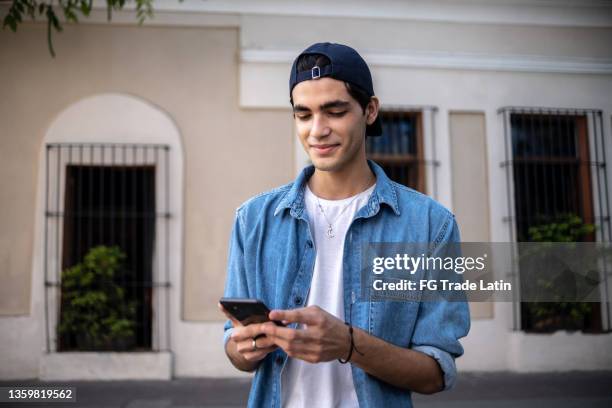 ragazzo adolescente che usa il telefono cellulare all'aperto - hispanic man foto e immagini stock