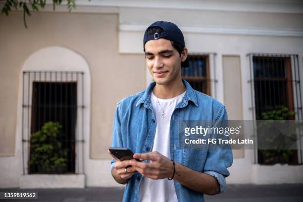 teenager boy using the mobile phone outdoors - foto's kijken op mobiel stockfoto's en -beelden