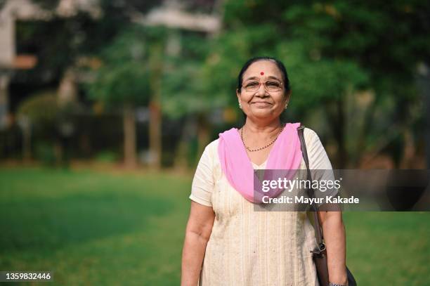 portrait of a senior woman standing in a park - indian old woman stock-fotos und bilder