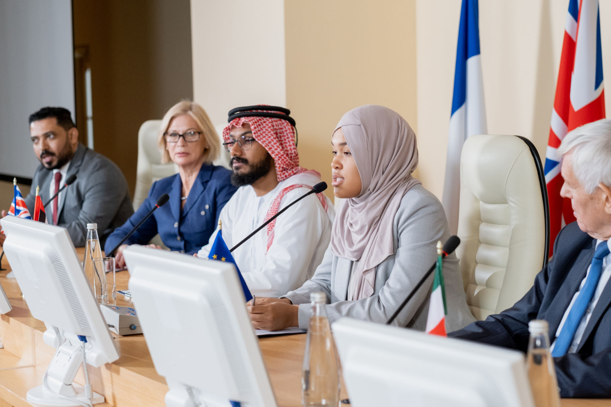 Young Muslim female in hijab making report to foreign colleagues Young Muslim female in hijab making report to foreign colleagues