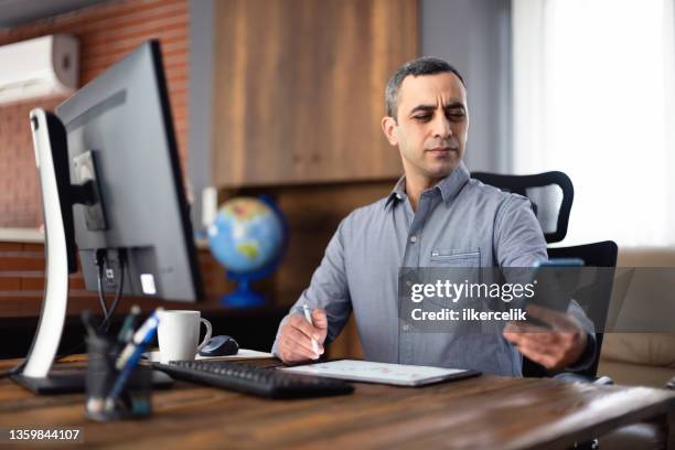 tired businessman in the office has difficulty to see texts on his smartphone, concept for the beginning of presbyopia just after the age of 40 years. - eyesight problem stock pictures, royalty-free photos & images