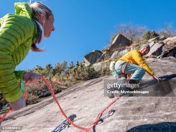 mountain climber belays teammate on multi-pitch route - zekeren stockfoto's en -beelden