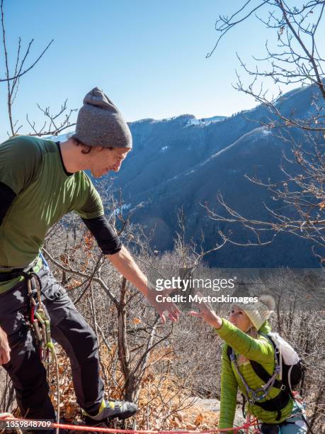 el alpinista recibe una mano amiga en la cima de la roca - dan peak fotografías e imágenes de stock