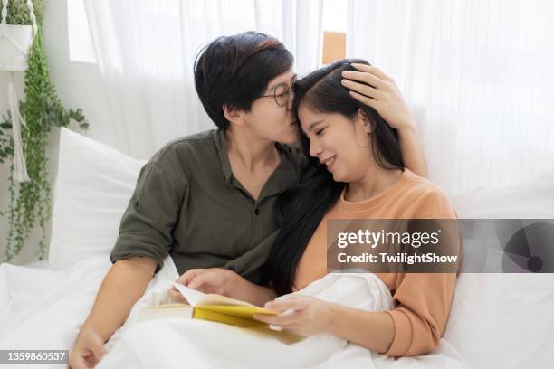 junges lesbisches liebespaar, das gemeinsam glücklich auf dem bett arbeitet, lgbtqia - good morning kiss images stock-fotos und bilder