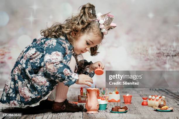 a girl is crouching playing with a set of coffee and cakes - gekrepptes haar stock-fotos und bilder