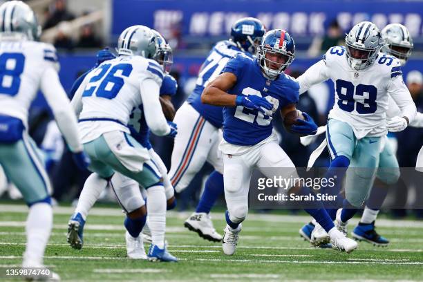 Devontae Booker of the New York Giants runs the ball and looks to avoid tackles by Tarell Basham and Jourdan Lewis of the Dallas Cowboys during the...