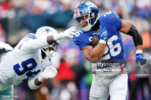 Saquon Barkley of the New York Giants runs the ball and looks to avoid a tackle by Randy Gregory of the Dallas Cowboys during the third quarter at...