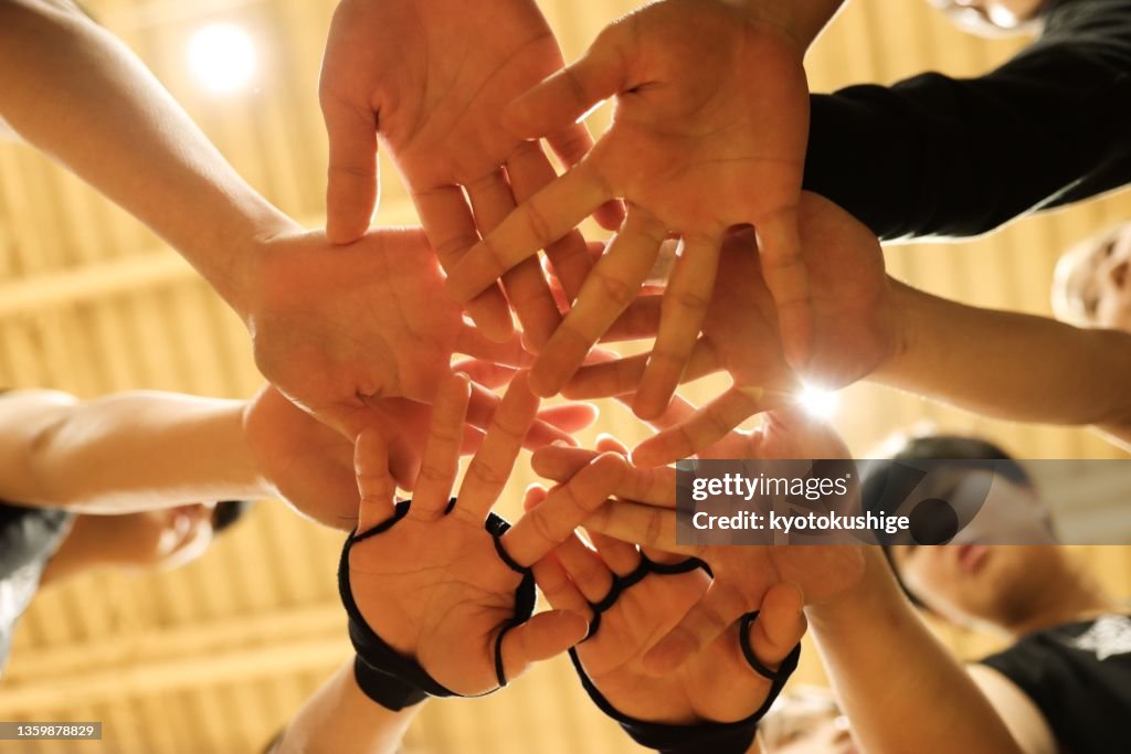 Athletes pile their hands together in a circle