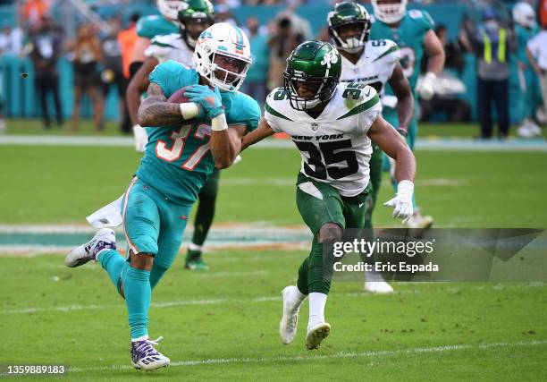 Myles Gaskin of the Miami Dolphins runs with the ball against Sharrod Neasman of the New York Jets in the fourth quarter at Hard Rock Stadium on...