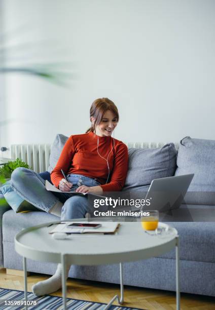 student life: a beautiful young woman using a laptop while having an online class at home - bank of canada stephen poloz speaks at durham college stockfoto's en -beelden