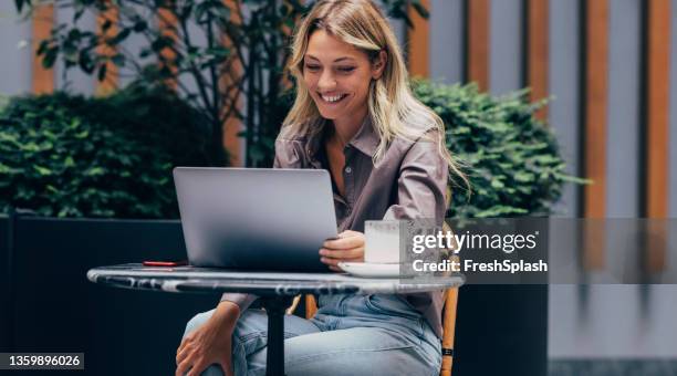 a beautiful woman sitting in a cafe and having an online language class - effortless imagens e fotografias de stock