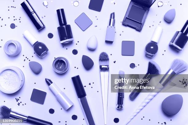 violet set for makeup application on white background with glittering confetti. many soft brushes, lipsticks, face powder, blushes, sponges, eyeshadows and nail polish. demonstrating very peri - color of 2022 year - blender explosion stock pictures, royalty-free photos & images
