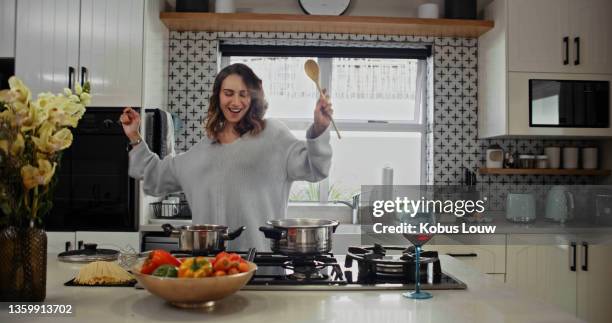 shot of a beautiful woman having fun while cooking alone at home - passion stock pictures, royalty-free photos & images
