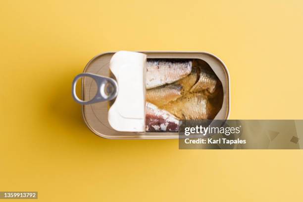 financial concepts preservation still life of canned sardines on a yellow background - estaño fotografías e imágenes de stock