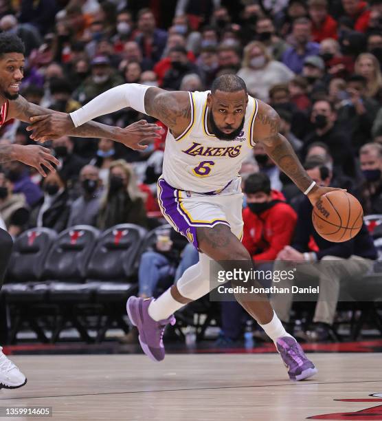 LeBron James of the Los Angeles Lakers drives past Alfonzo McKinnie of the Chicago Bulls at the United Center on December 19, 2021 in Chicago,...