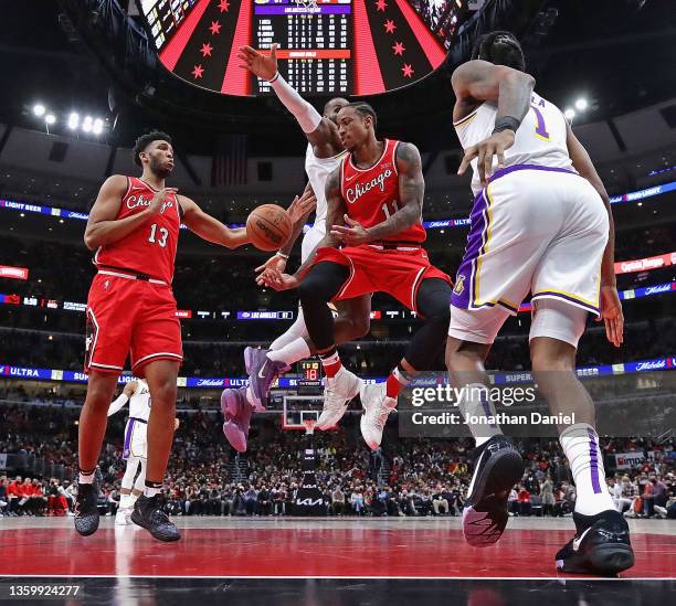 DeMar DeRozan of the Chicago Bulls passes to teammate Tony Bradley between Trevor Ariza and LeBron James of the Los Angeles Lakers at the United...